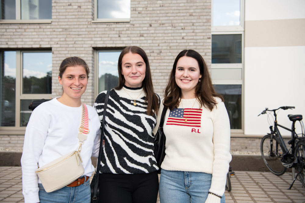 Drei Frauen stehen vor einem Neubau und lächeln in die Kamera.