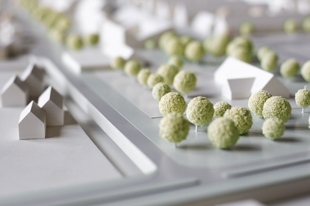 Architekturmodell mit weißen Häusern und hellgrünen Bäumen