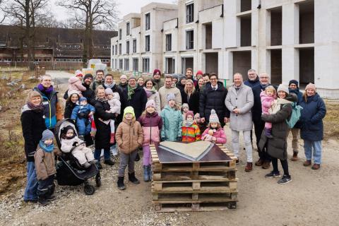 Eine Gruppe Menschen vor einem Gebäude. Vor ihnen liegt ein Herz aus Beton.