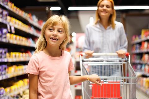 Ein Mädchen zusammen mit seiner Mutter beim Einkaufen.